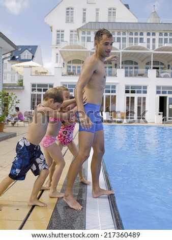 Children pushing man in pool