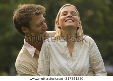 Mid adult man embracing a mid adult woman from behind and smiling