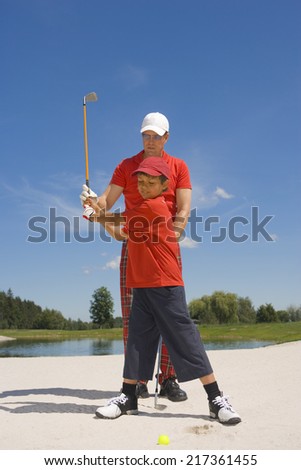 Mid adult man giving golf training to his son