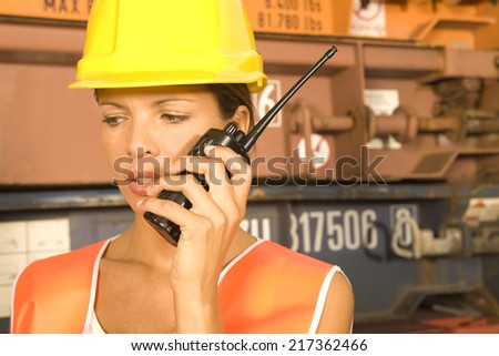 Close-up of a female dock worker talking on a walkie-talkie