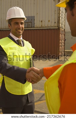 Businessman shaking hands with a male dock worker