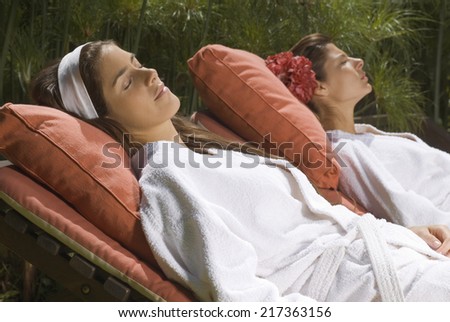 Two young women resting on lounge chairs