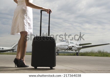 Woman standing and holding her luggage at an airport