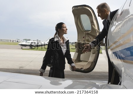 Pilot helping a cabin crew at the door of a private airplane