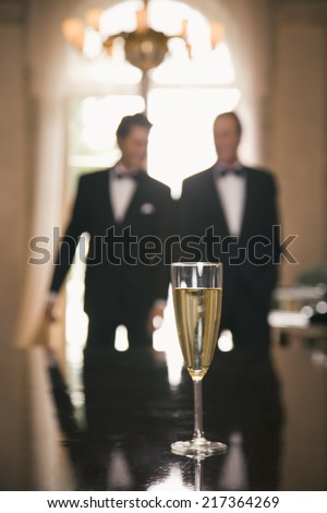 Champagne flute on a table with two men in the background