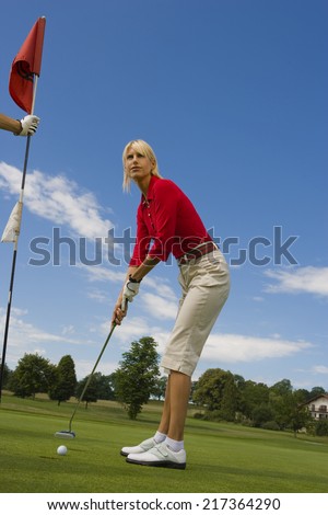 Side profile of a mid adult woman playing golf on a golf course