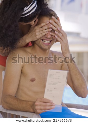 Woman covering man\'s eyes near pool