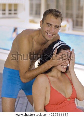 Man covering woman's eyes near pool