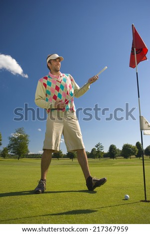 Mid adult man playing golf on a golf course and smiling
