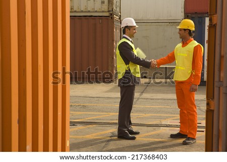 Side profile of a businessman shaking hands with a male dock worker
