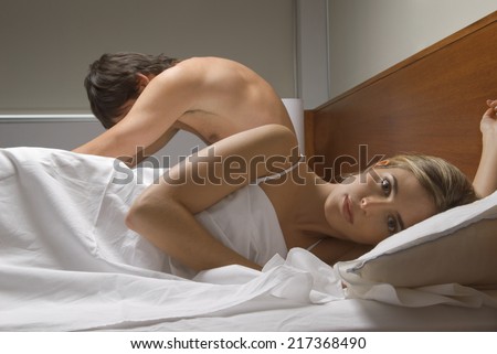 Couple ignoring each other in bed
