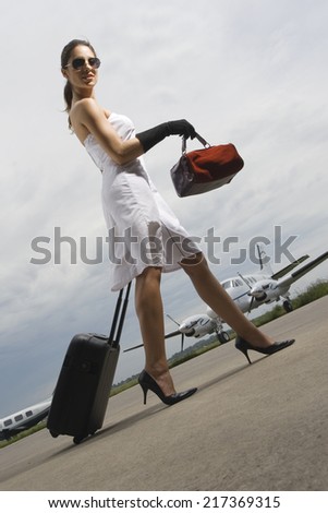 Side profile of a young woman pulling her luggage