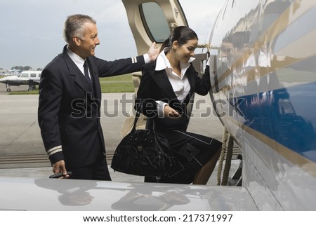 Cabin crew entering in a private airplane with a pilot standing behind her