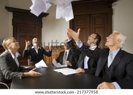 Businesspeople throwing papers in the air