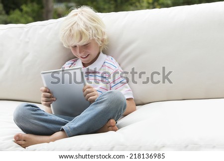 Smiling boy using digital tablet on outdoor sofa