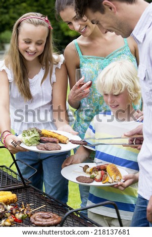 Happy family standing at barbecue grille