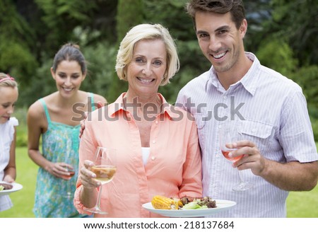 Portrait of smiling mother and son with barbecue and wine