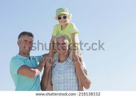 Portrait of smiling multi-generation men against blue sky