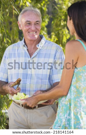 Senior Man Serving Food At Family Barbeque