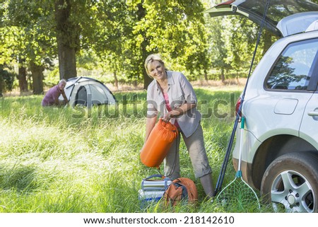 Senior Couple Unpacking Car For Camping Trip In Countryside