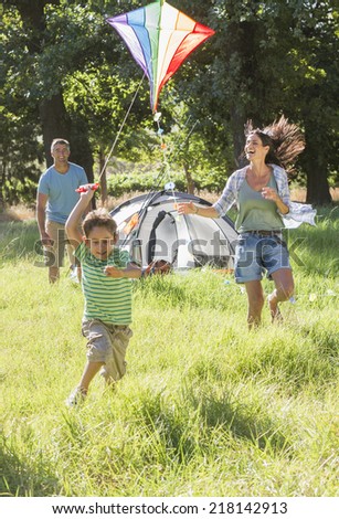 Family Flying Kite On Camping Holiday In Countryside