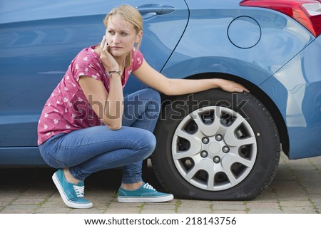Woman With Flat tire On Car Phoning For Assistance