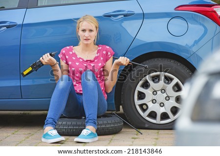 Frustrated Woman Trying To Change Flat tire On Car
