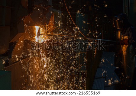 operator tapping molten metal in iron casting factory