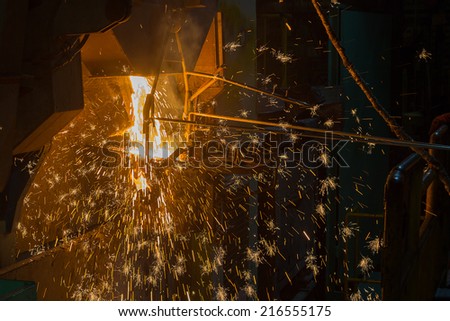 operator tapping molten metal in iron casting factory