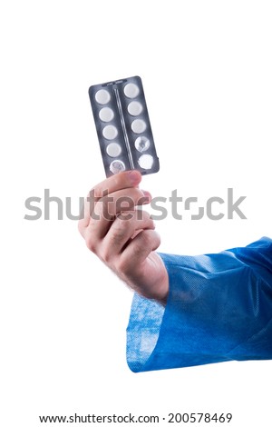 Hand wearing medical apron holding a  pill