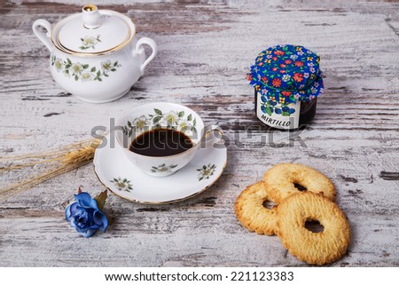 coffee in porcelain cups with biscuits,jam and radio on a rustic wooden