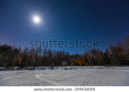 Mystical frozen winter lake in magic moonlight at star night