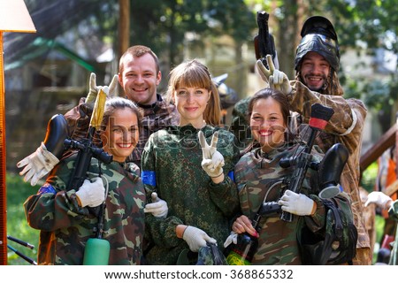 Happy team of five paintball players outdoors