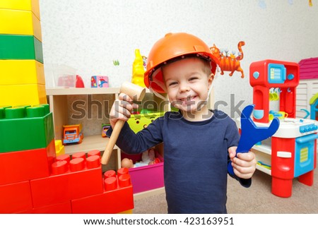 Funny little repairman with toy hammer and wrench in daycare
