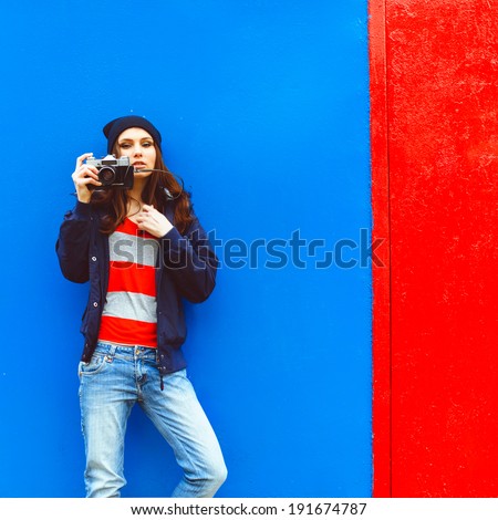 portrait of a beautiful hipster girl with a camera on the background photon makes blue walls and red doors