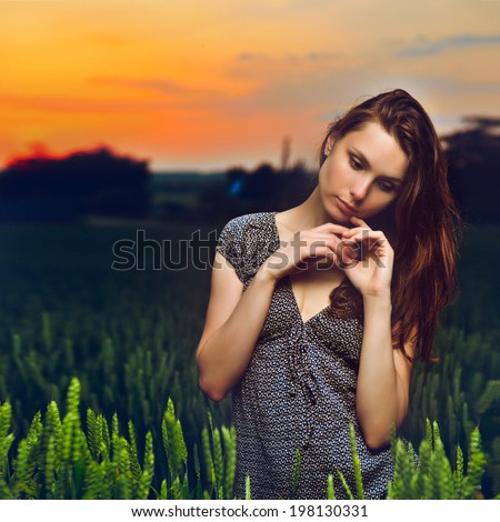 portrait of beautiful young woman standing in green field at sunset beautiful young woman standing in green field at sunset