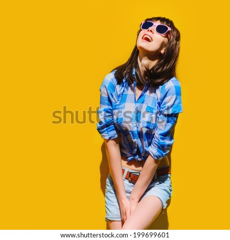 portrait of a beautiful girl in bright blue shirt girl with glasses on a background of orange walls background