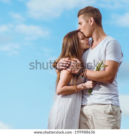 Portrait of a beautiful young couple in love on the blue sky background. Wedding couple fashion shoot.