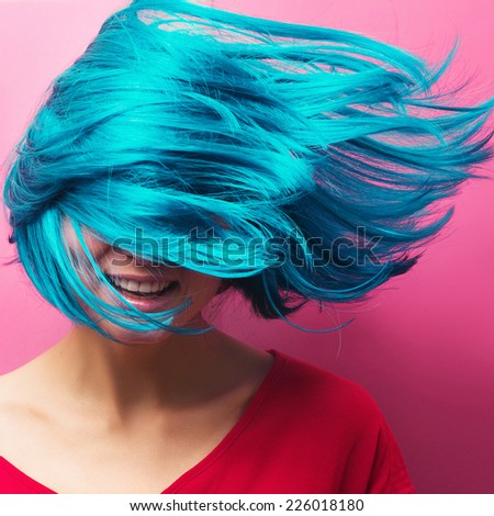 isolated studio portrait of a beautiful girl with turquoise hair in motion on a pink background