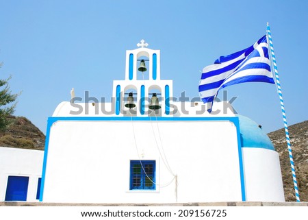 Santorini, Greece: traditional typical white and blue church, with Greek flag and three bells.