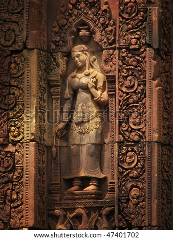 Lovely Apsara (dancing woman) red sandstone carving at the Banteay Srei temple (temple of women) near Angkor Wat (Siem Reap, Cambodia).