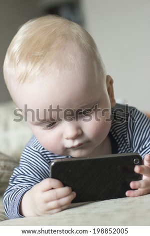 baby boy playing with a smart studying it carefully with much interest
