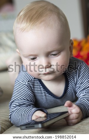baby boy playing with a smart phone studying it carefully with interest