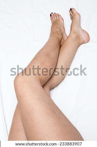 Shaved and smooth woman\'s long legs. Isolated on white with cofee and cake