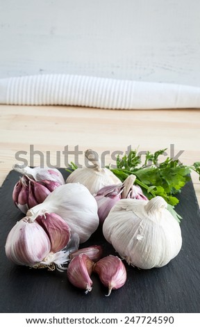 Composition of purple garlic with parsley on wooden board