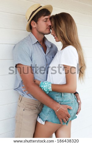 Lifestyle portrait of young sensual happy couple kissing at summertime at white background.