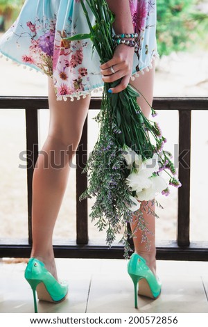 Close up fashion image of woman holding cute summer bouquet, wearing tender mint dress and neon green classic pumps. Vintage style.