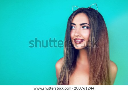 Young happy smiling pretty girl posing at turquoise background wearing stylish diamond wreath. Bright instagram colors, natural make up.