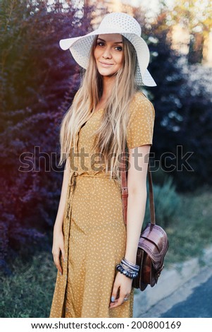 Young happy pretty woman posing in city garden in stylish retro hat and outfit, smiling and having fun alone. Retro style.