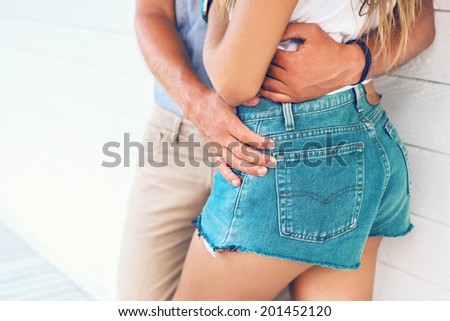 Close up fashion image of young sexy couple,hugs at light background, wearing retro jeans shoots.